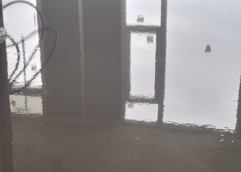 Reflection of a window wall and ceiling pipes in a wet self-leveling floor