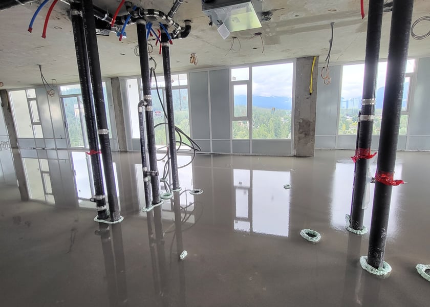 Self-leveling compound poured across a unit floor with a mountain view through the windows