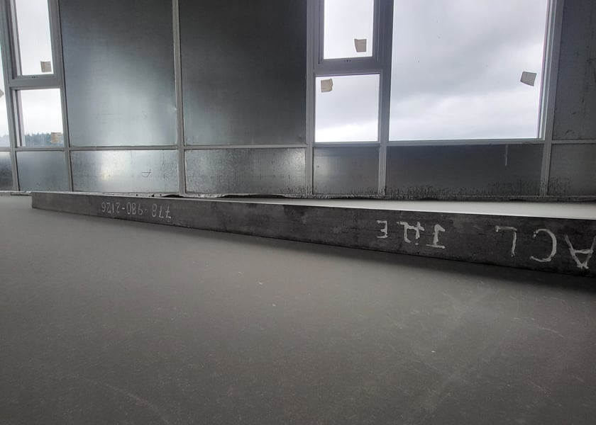 Wide view of a straightedge tool laid along a window wall on a self-leveled concrete floor